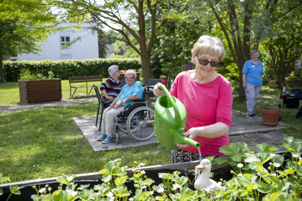 Korian_4003_Haus am grünen Weg Lollar_Garten_Bewohnerin_Blumengießen