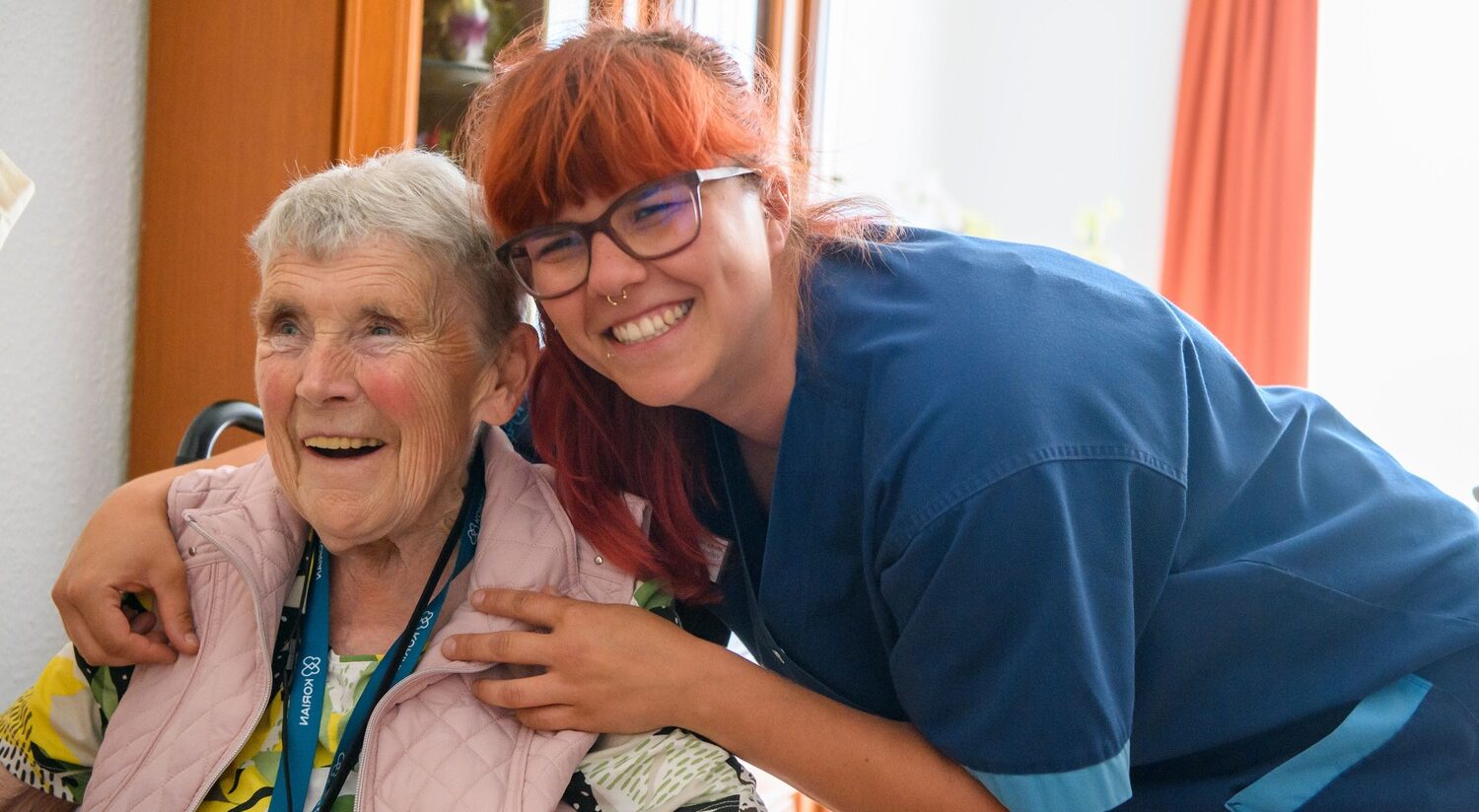 Weibliche Pflegekraft umarmt ältere Frau im Rollstuhl bei der häuslichen Betreuung durch den ambulanten Korian Pflegedienst Pflege und Betreuung zuhause am Jahnpark in Altenburg.