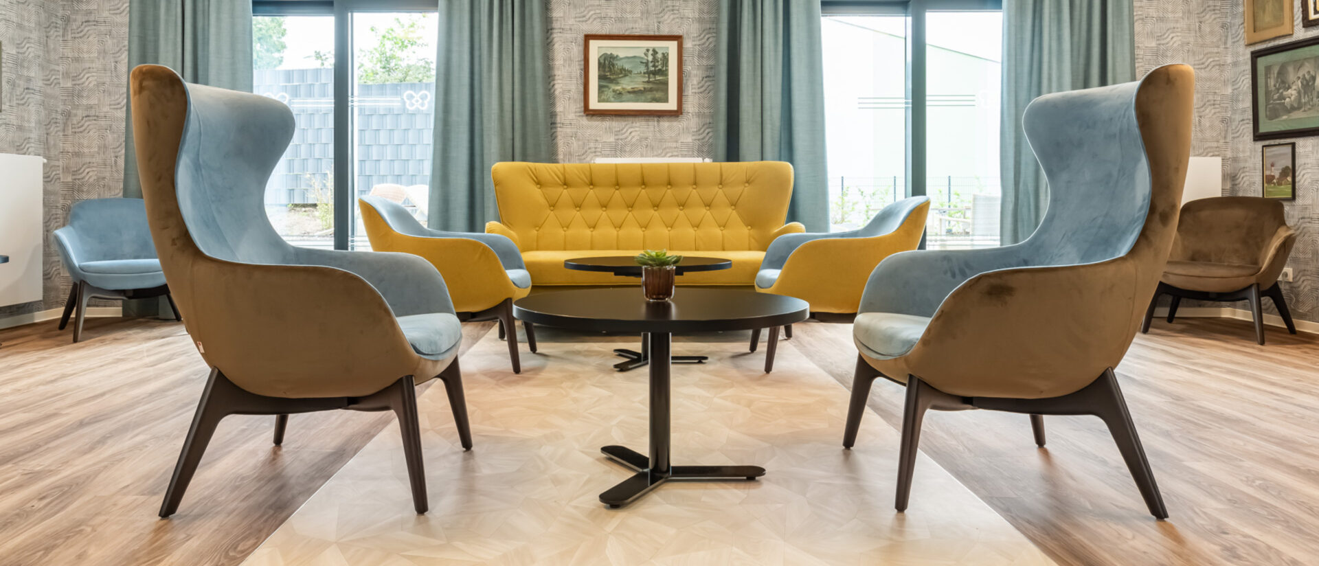 Bewohner:innen des Pflegeheims am Carree sitzen im hellen Gemeinschaftsraum in Riegelsberg und trinken gemeinsam Kaffee.