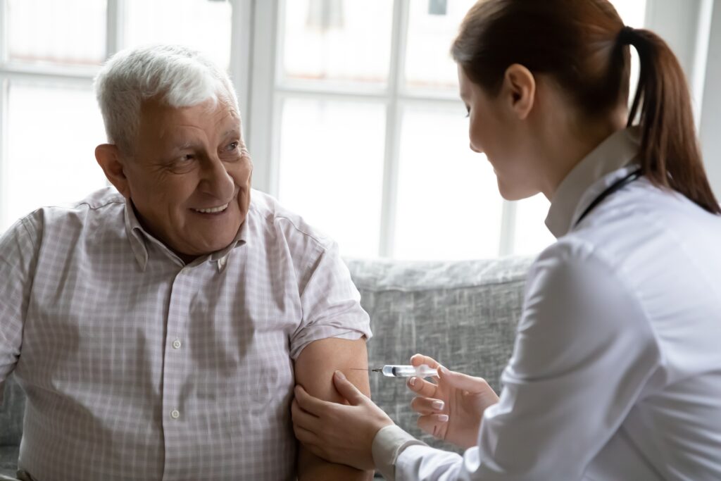 Attentive,Female,Nurse,Make,Arm,Injection,To,Positive,Senior,80s