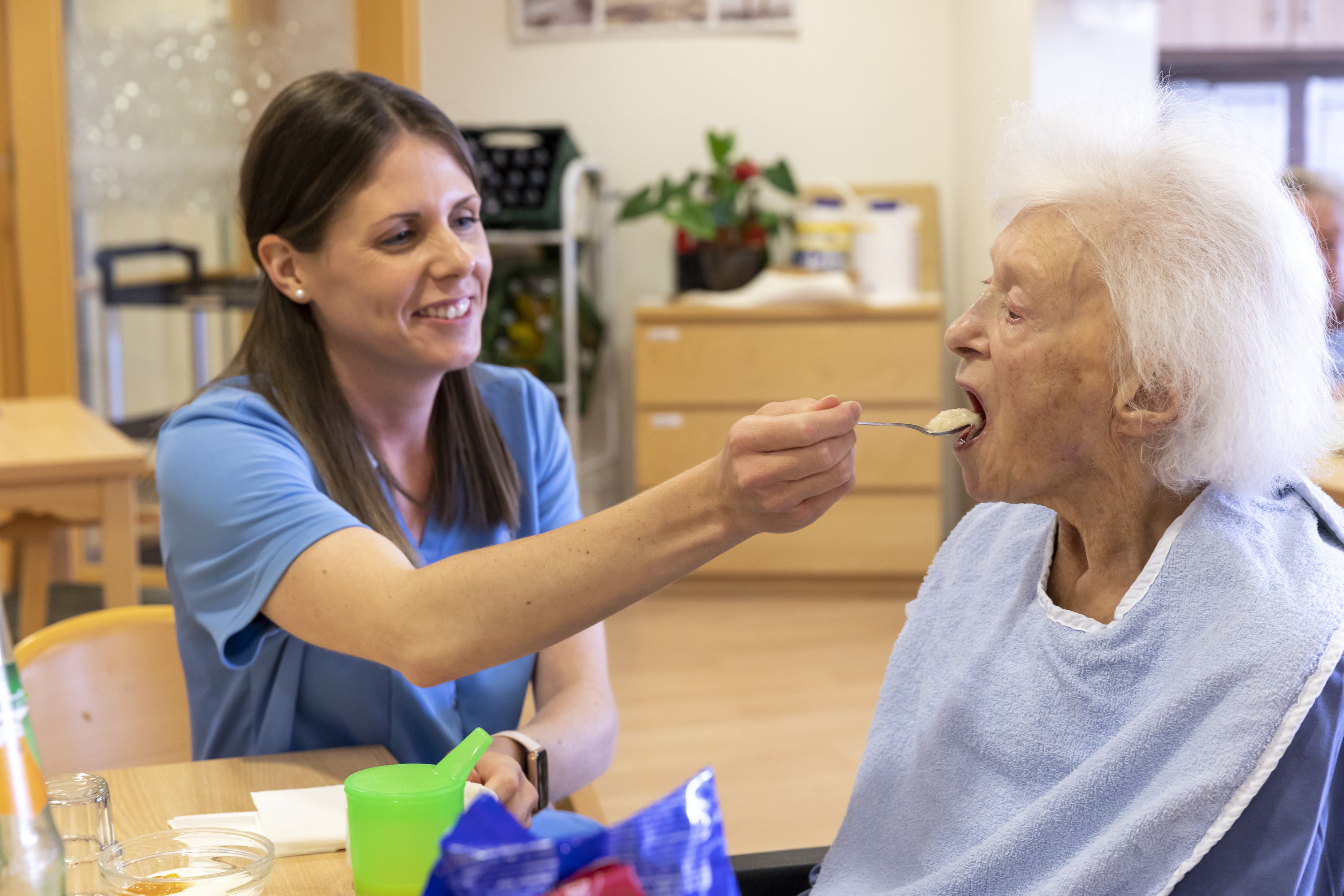 Eine Pflegerin füttert eine Seniorin mit Schluckstörungen (Dysphagie) im Pflegeheim